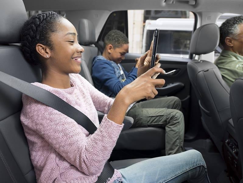Child passenger using smartphone in the backseat